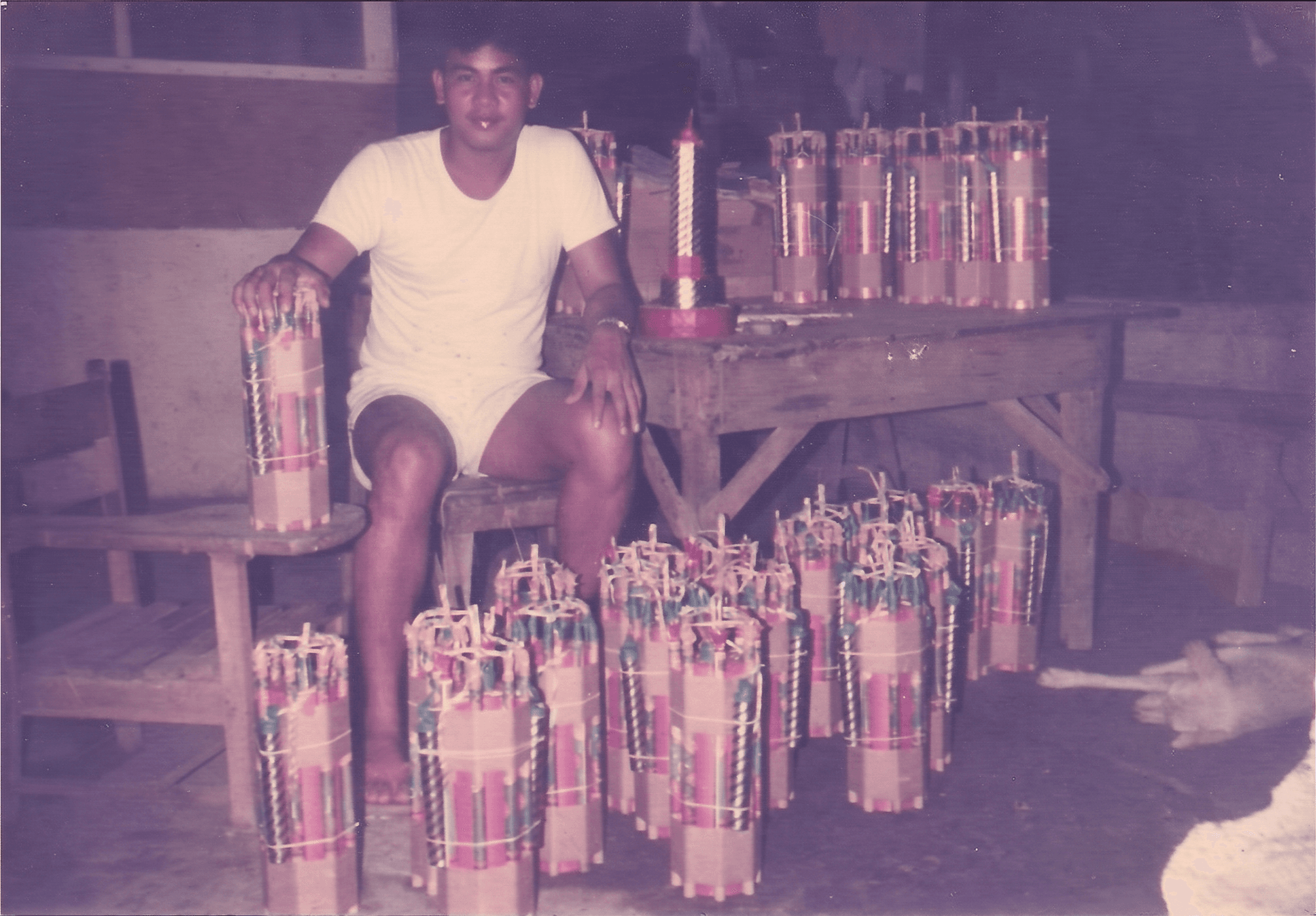 A young Vincent Lebrilla in the family workshop, seated among hand-built firecracker bundles