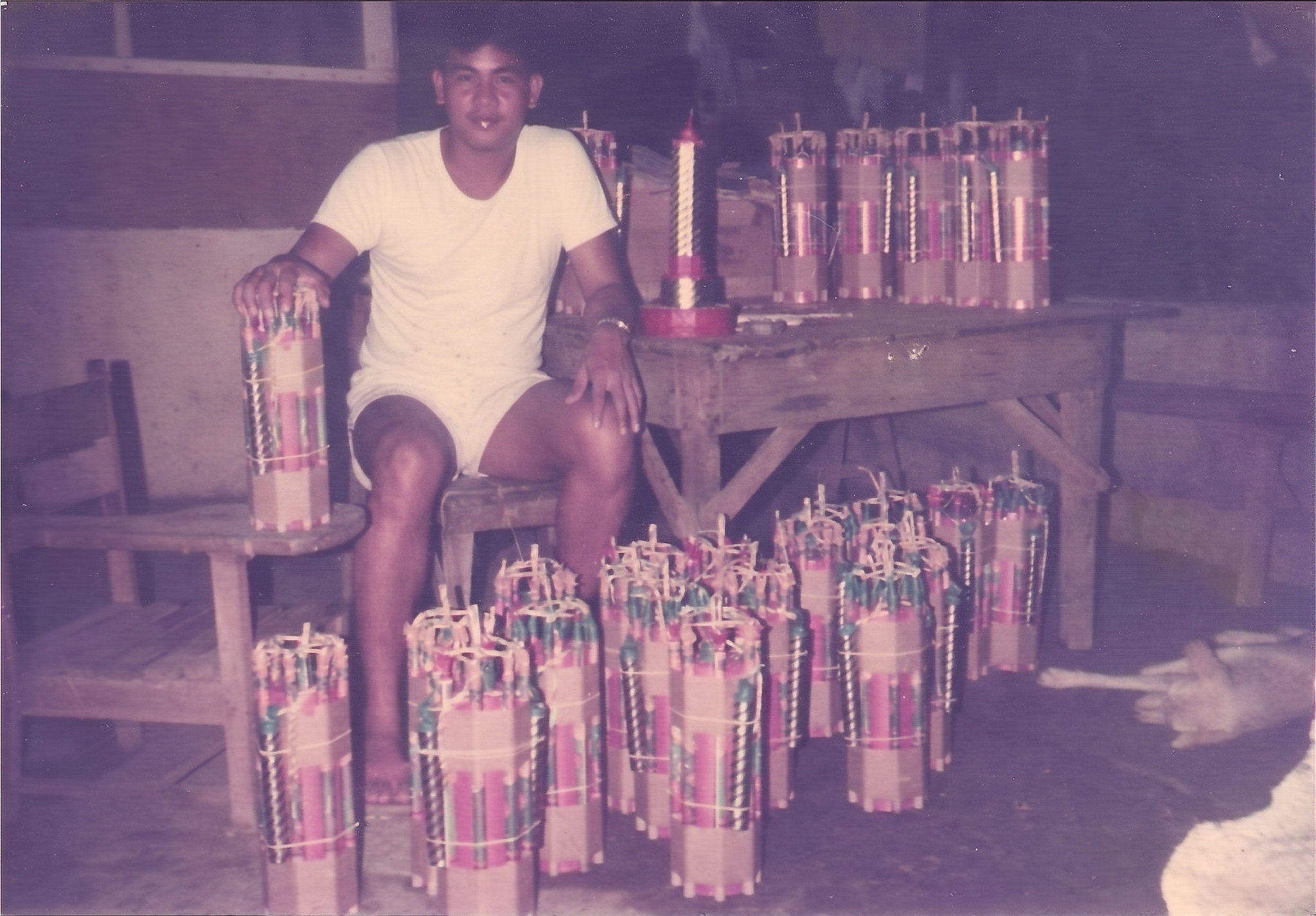 A young Vincent Lebrilla in the family workshop, seated among hand-built firecracker bundles
